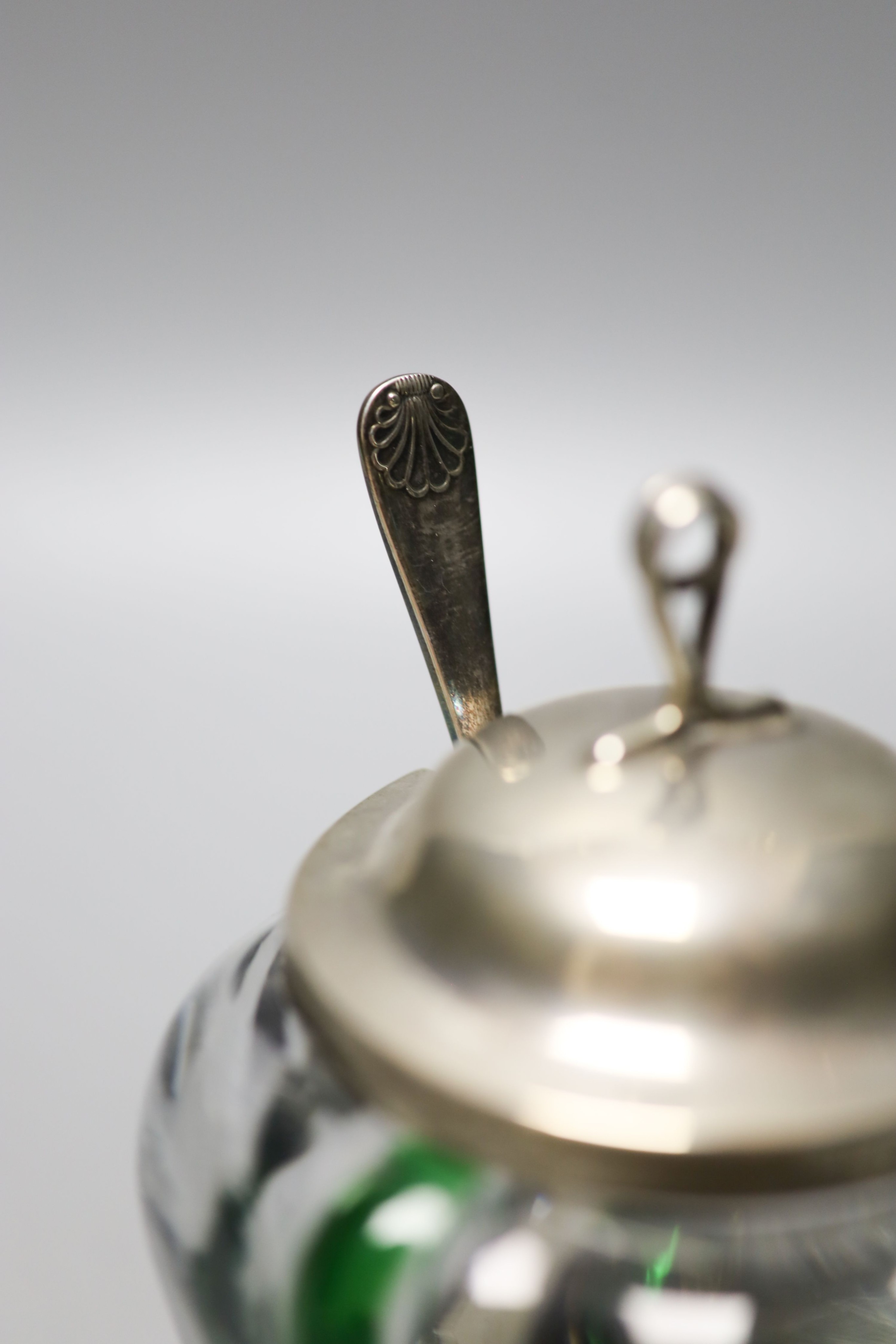 A late Victorian Art Nouveau silver mounted green and clear glass preserve pot, the glass probably James Powell & Sons, Mappin & Webb, London, 1900, 13.2cm, with later associated spoon